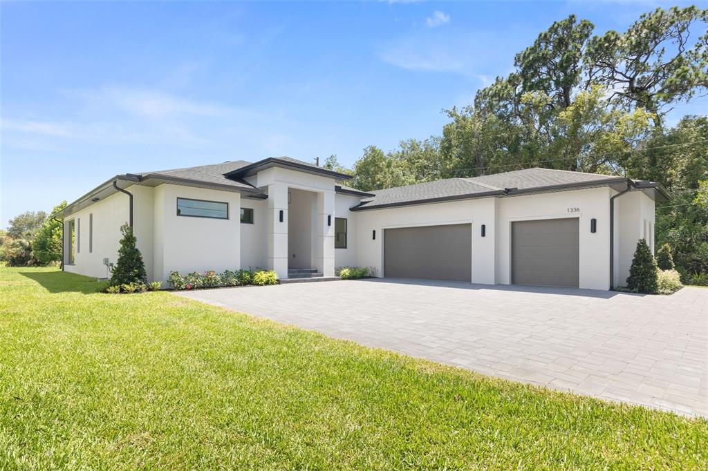 A modern single-story house features a white stucco exterior, a paved driveway, and two garages — 1336 HAYS ROAD, TARPON SPRINGS, FL
