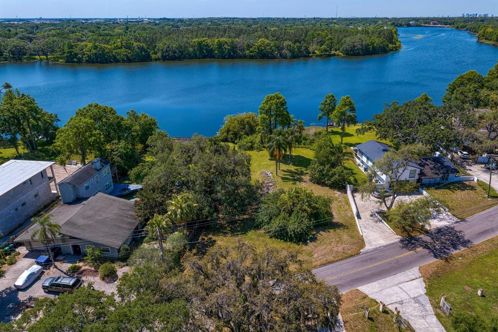 An aerial view shows two houses on a grassy lot bordering a large lake — 4607 E RIVER HILLS DRIVE, TAMPA, FL