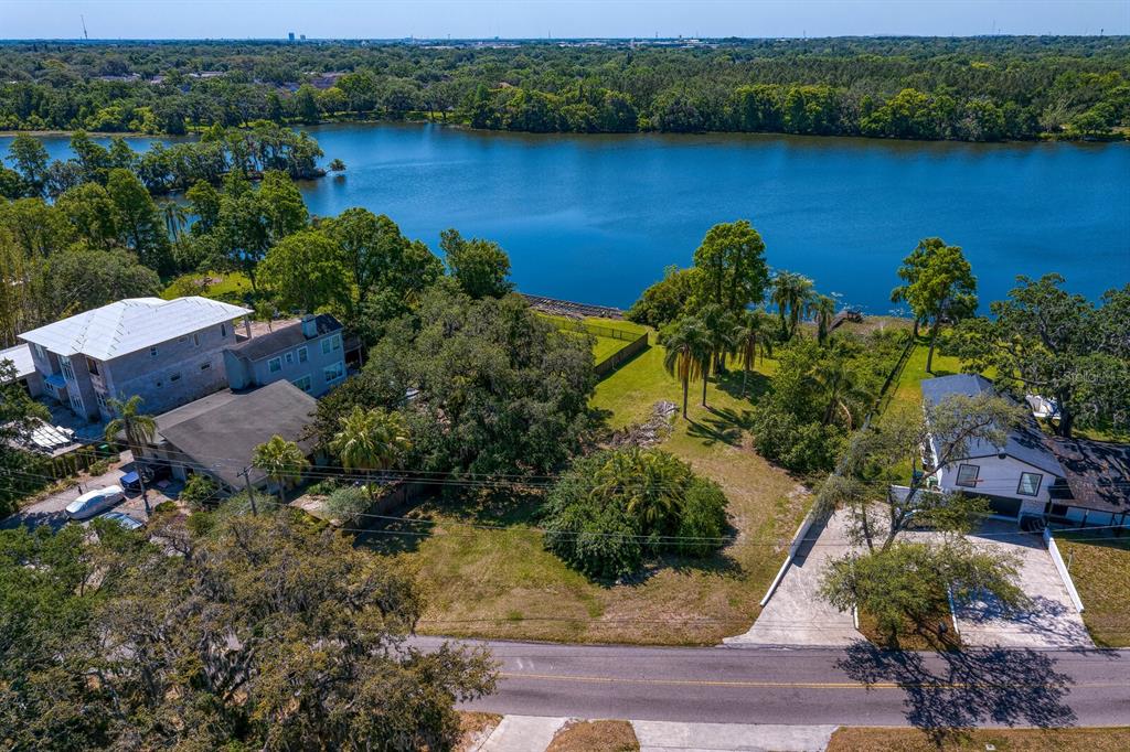 An aerial view shows a vacant lot situated between two houses along a lakefront — 4607 E RIVER HILLS DRIVE, TAMPA, FL
