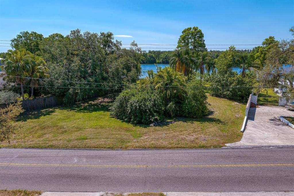 An elevated view shows a grassy vacant lot with trees and a lake in the background — 4607 E RIVER HILLS DRIVE, TAMPA, FL