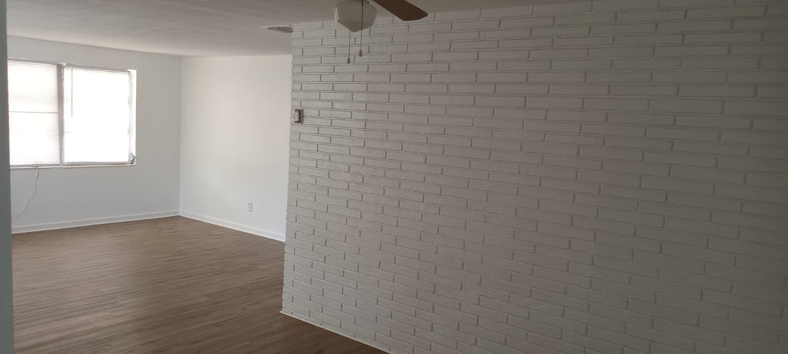 A room with light wood-look flooring and a white painted brick accent wall — 131 E Camphor Street, FL 33825, FL