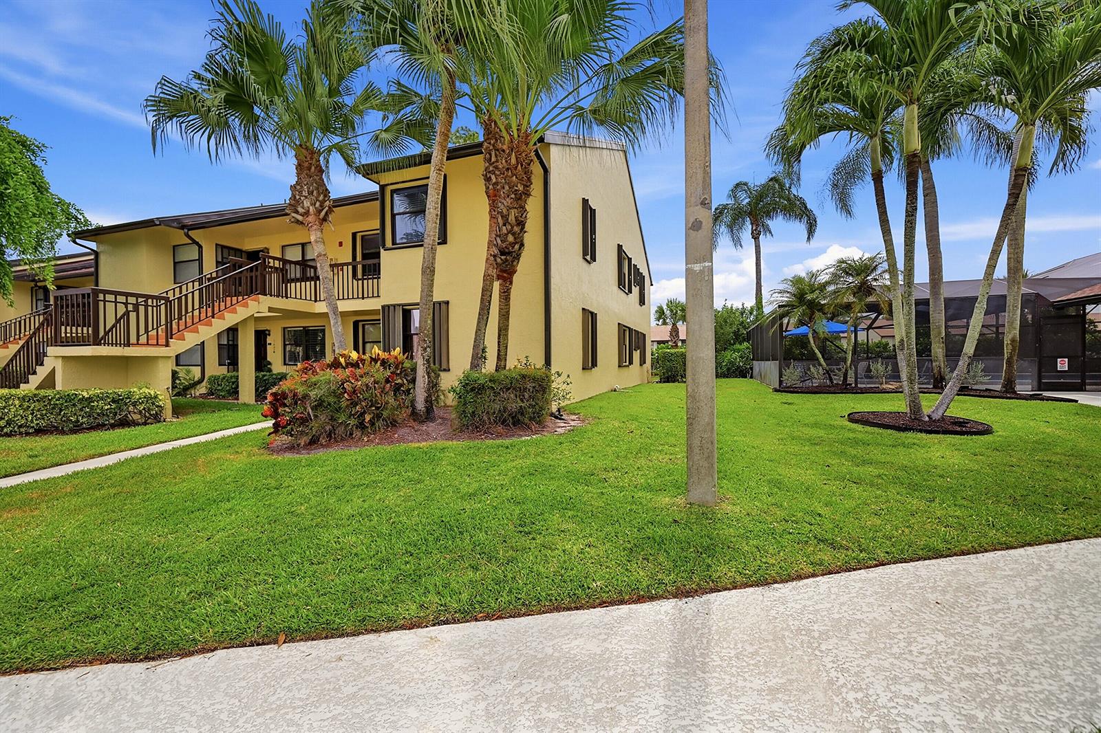 A yellow two-story apartment building with palm trees and a grassy lawn — 4699 E Lucerne Lakes Boulevard # 206, Lake Worth FL 33467, LAKE WORTH, FL