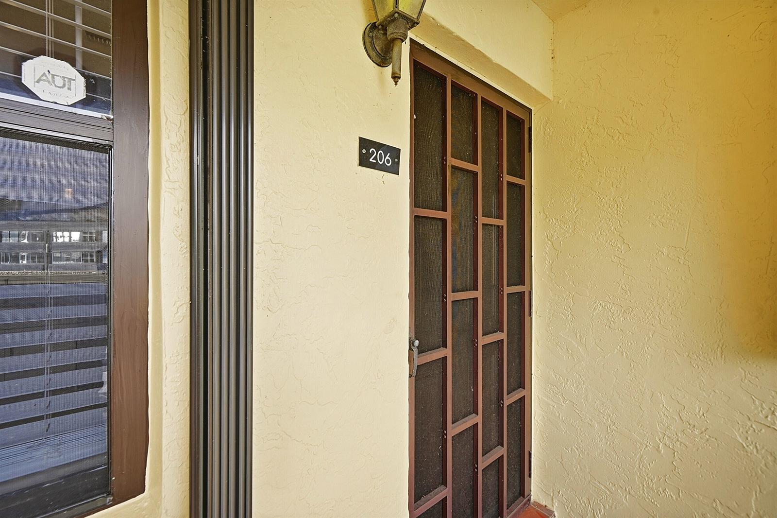 The exterior entrance of a residential unit features a screen door and unit number 206 — 4699 E Lucerne Lakes Boulevard # 206, Lake Worth FL 33467, LAKE WORTH, FL
