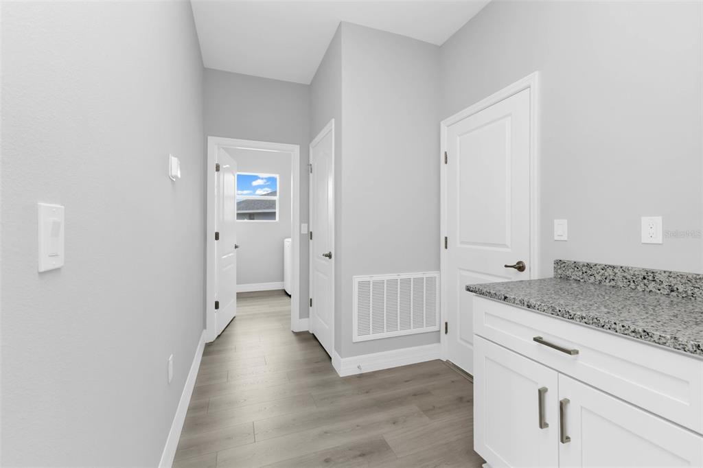 A laundry room features light gray walls, wood-look flooring, white cabinets, and granite countertops — 17022 ESPANA CIRCLE, PUNTA GORDA, FL