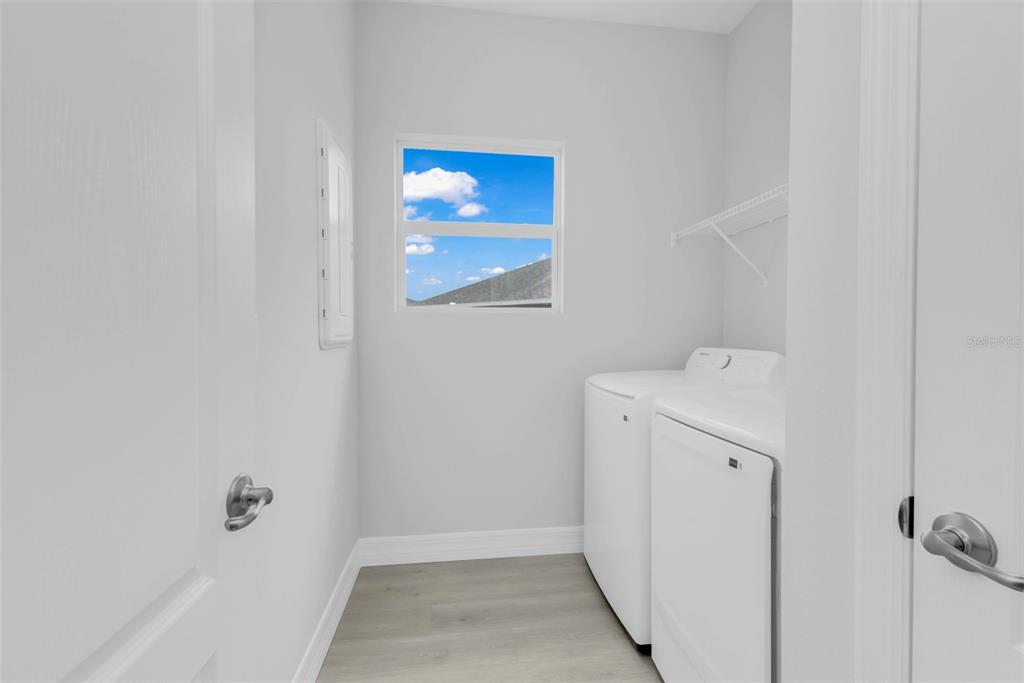 A laundry room features white walls, light wood-look flooring, a window, and two white appliances — 17022 ESPANA CIRCLE, PUNTA GORDA, FL