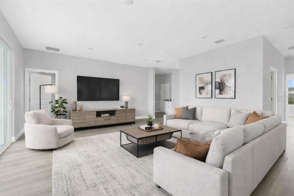A modern living room features a large sectional sofa, a television, and light wood flooring — 17022 ESPANA CIRCLE, PUNTA GORDA, FL