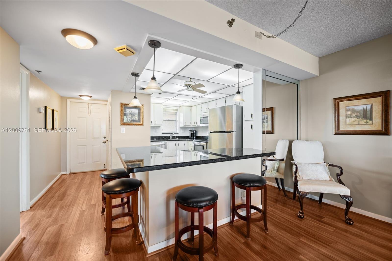 A kitchen with a breakfast bar, dark countertops, and stools opens to a dining area — 3300 W Rolling Hills Cir # 510, Davie FL 33328, DAVIE, FL