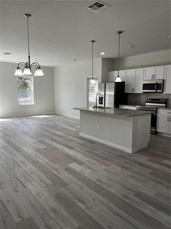A kitchen with a center island and dining area features light wood-look flooring throughout — 5312 SW 162ND PLACE ROAD, OCALA, FL
