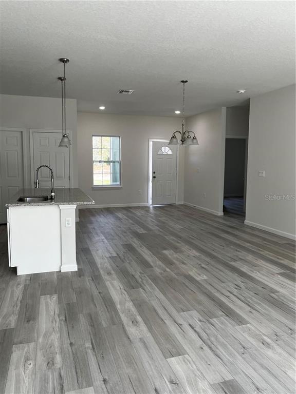 A kitchen island with a sink sits in an open-concept room with gray flooring — 5312 SW 162ND PLACE ROAD, OCALA, FL