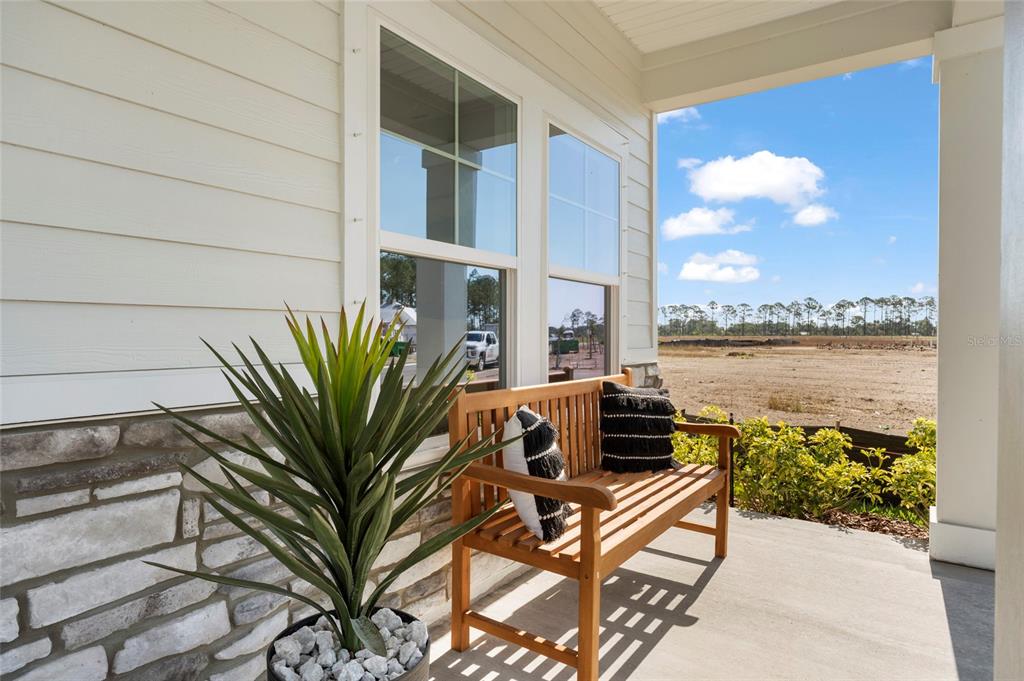 A wooden bench sits on a covered porch with stone siding and a potted plant — 46 PEGASUS ROAD, FLAGLER BEACH, FL