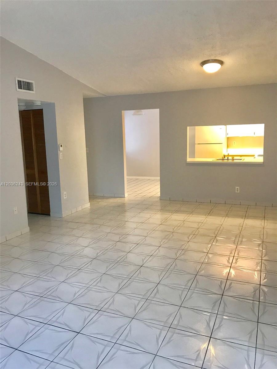 A room with white tiled floors, light gray walls, and a kitchen pass-through window — 9810 Hammocks Blvd # 202, Miami FL 33196, MIAMI, FL