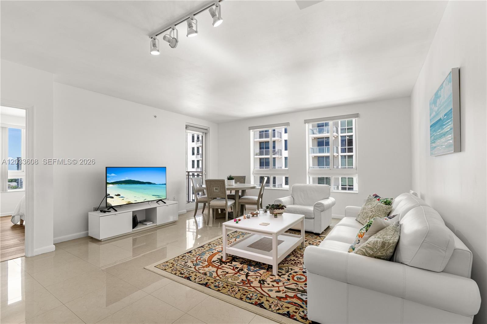 A bright living room features white walls, tile flooring, a white sofa, and dining area — 7350 SW 89th St # 1610S, Miami FL 33156, MIAMI, FL
