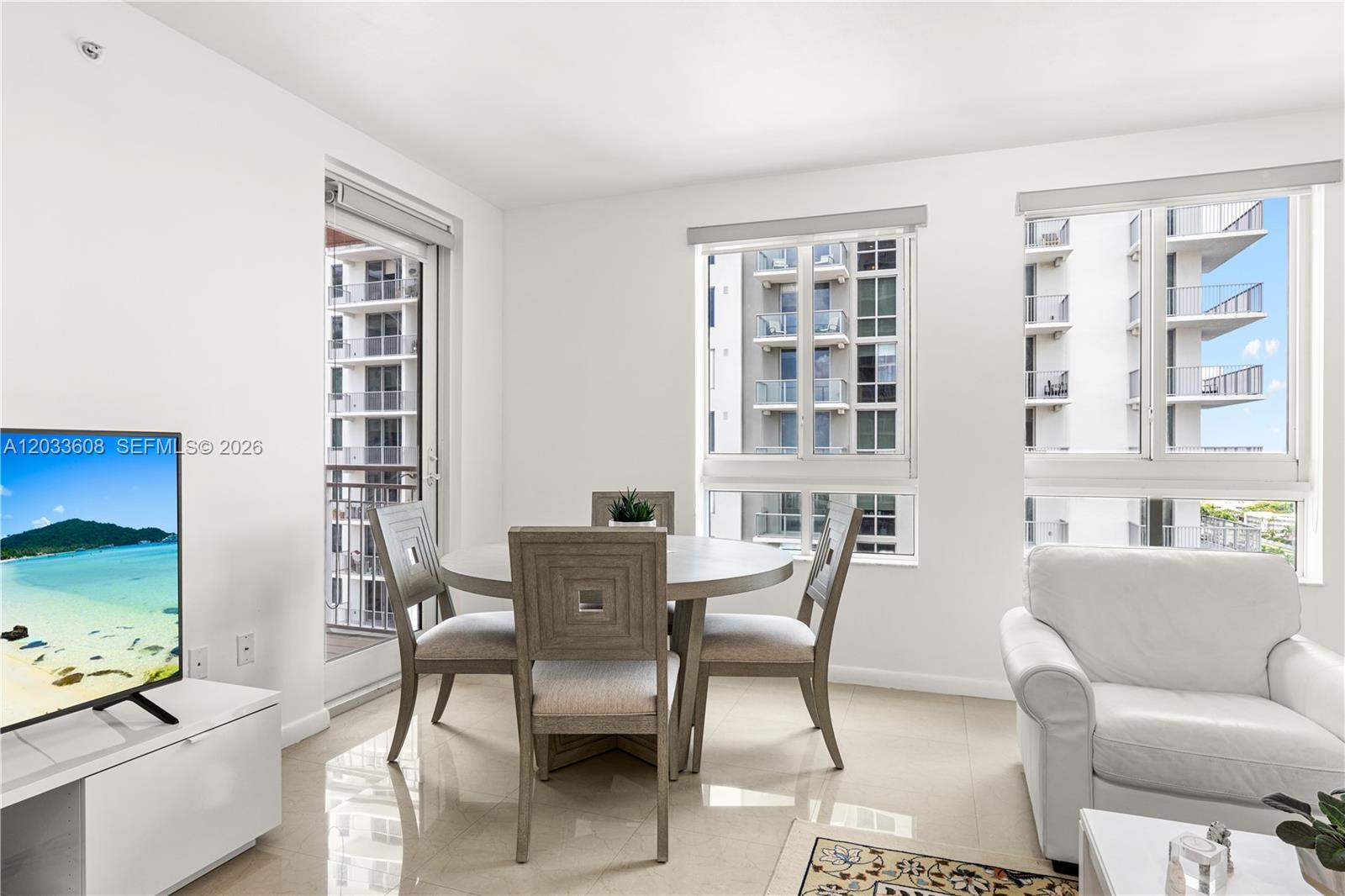 A dining area with a round table and chairs sits between a balcony and windows — 7350 SW 89th St # 1610S, Miami FL 33156, MIAMI, FL