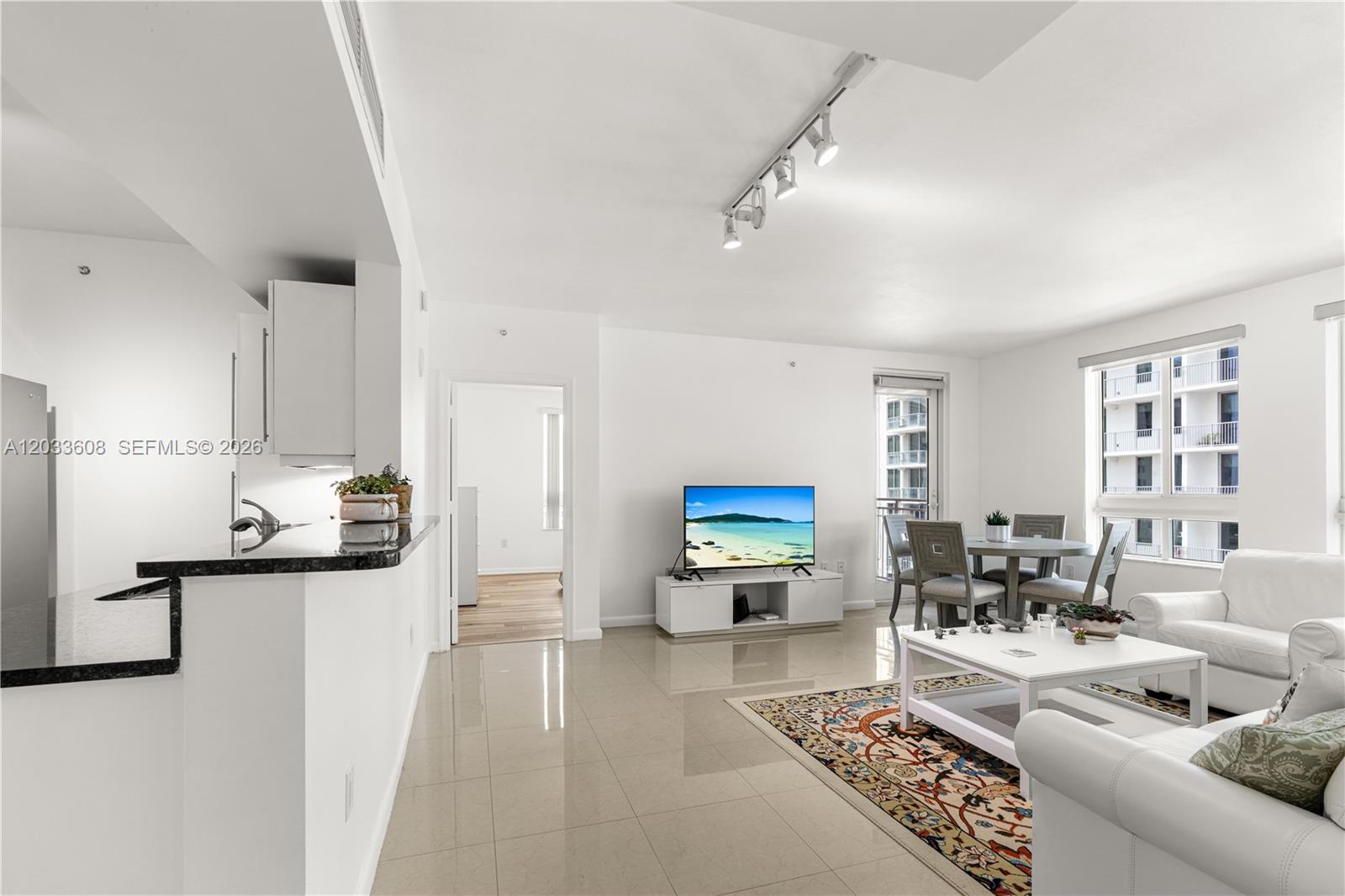 A bright living room features white walls, tile flooring, a dining area, and a kitchen — 7350 SW 89th St # 1610S, Miami FL 33156, MIAMI, FL