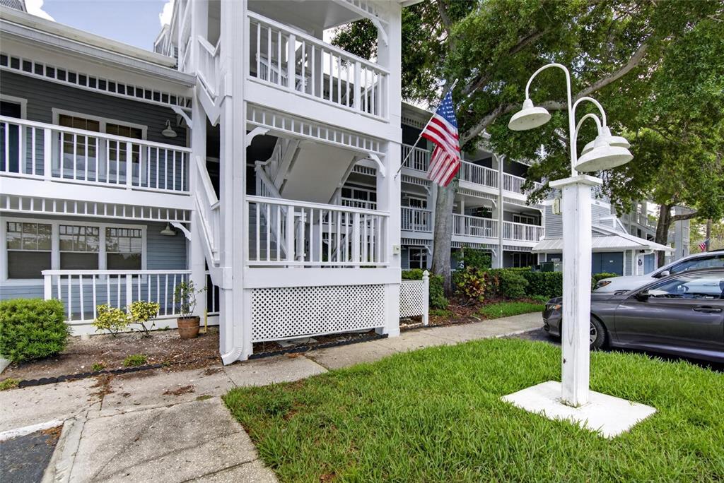 A multi-story apartment building with white railings, a staircase, and a flag on display — 2599 DOLLY BAY DRIVE UNIT 305, PALM HARBOR, FL