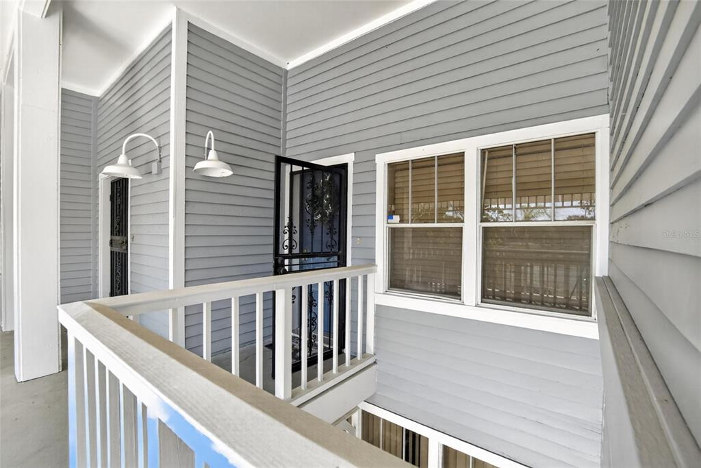An exterior view of a gray-sided balcony featuring a white railing and two light fixtures — 2599 DOLLY BAY DRIVE UNIT 305, PALM HARBOR, FL