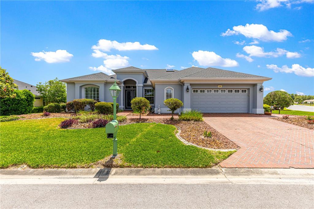 A single-story house with a gray exterior, a brick driveway, and a green mailbox — 9280 SE 126TH STREET, SUMMERFIELD, FL