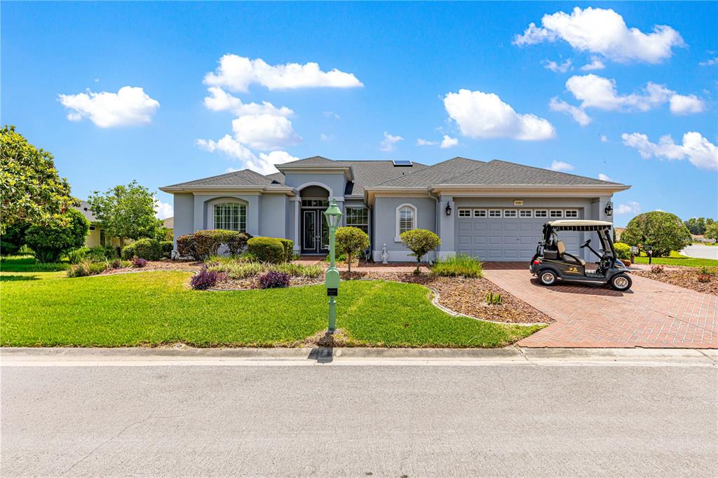A single-story gray house with a brick driveway and a golf cart parked outside — 9280 SE 126TH STREET, SUMMERFIELD, FL
