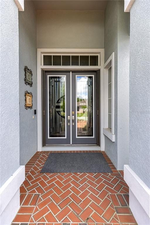 A front entryway features double glass doors, a brick floor in a herringbone pattern, and stucco walls — 9280 SE 126TH STREET, SUMMERFIELD, FL