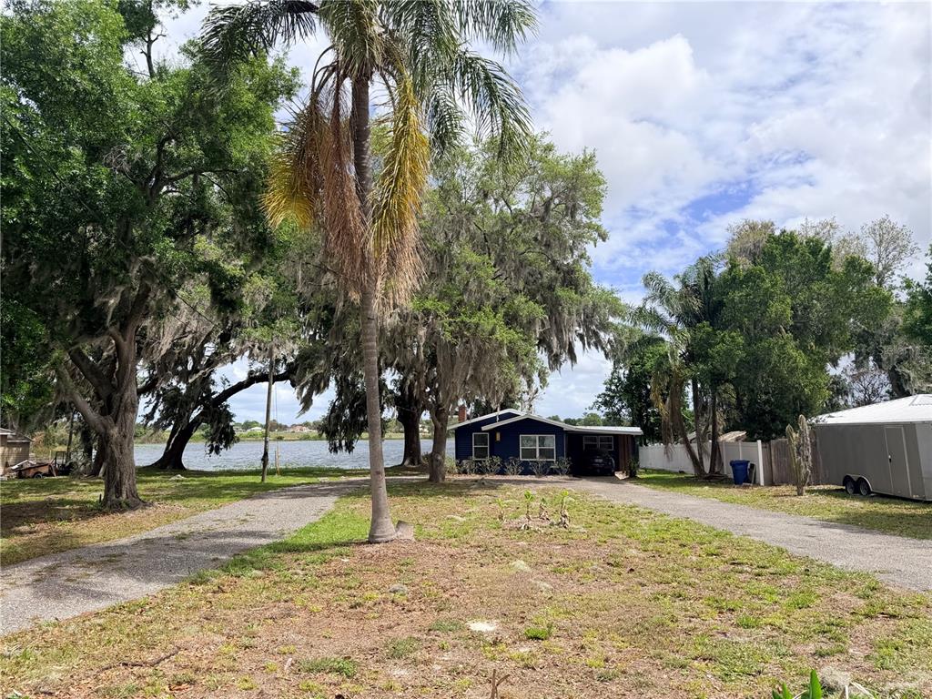 A blue house sits on a large lot with mature trees and a lake view — 915 W MAIN STREET, LAKE HAMILTON, FL