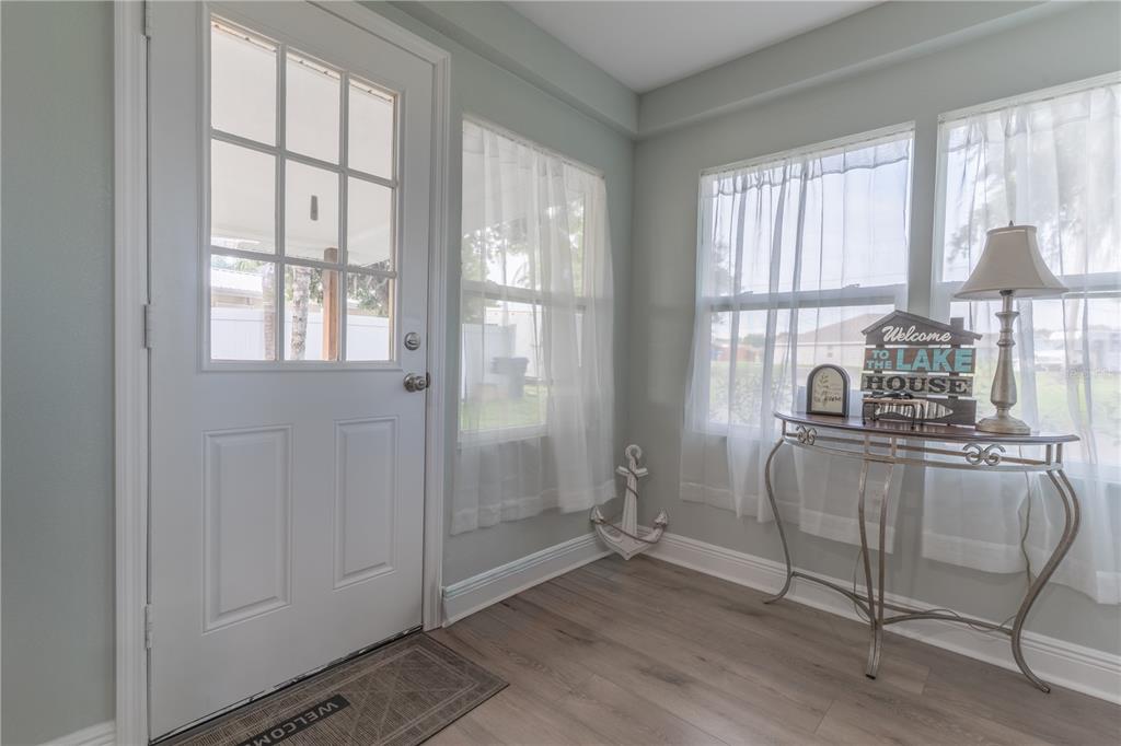 An entryway features light wood-look flooring, a white paneled door, and a decorative console table — 915 W MAIN STREET, LAKE HAMILTON, FL