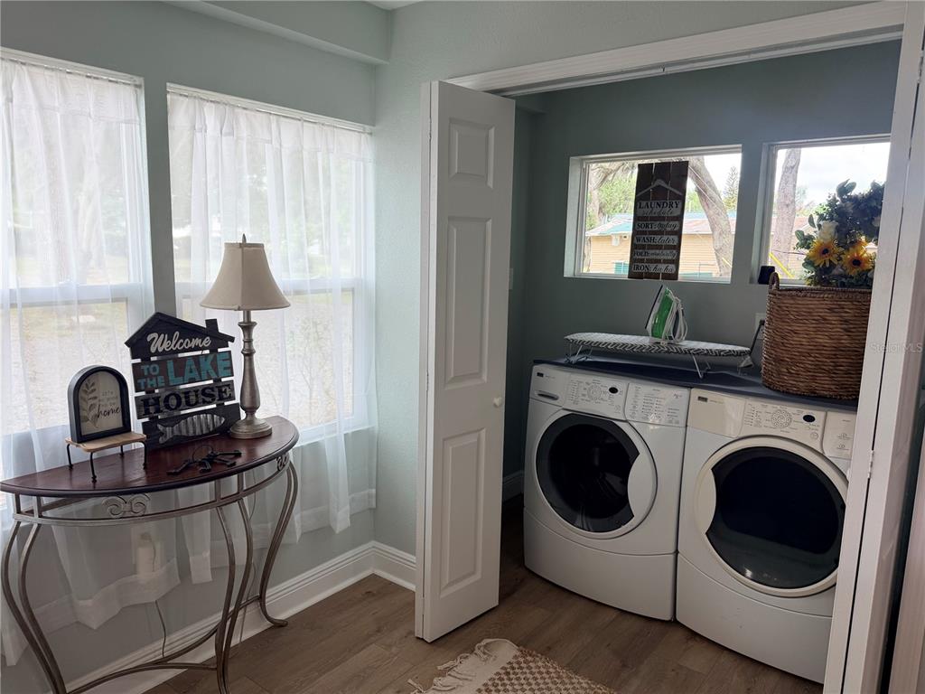 A laundry room features white appliances, an ironing board, and a console table by windows — 915 W MAIN STREET, LAKE HAMILTON, FL