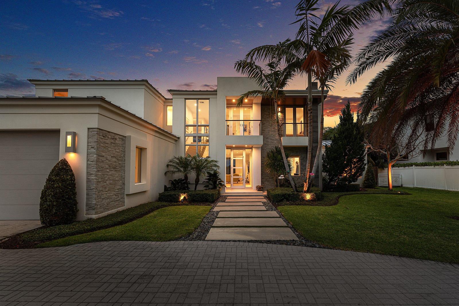 A two-story modern house with stone accents, palm trees, and a paved walkway at dusk — 1508 Lake Drive, Delray Beach FL 33444, DELRAY BEACH, FL