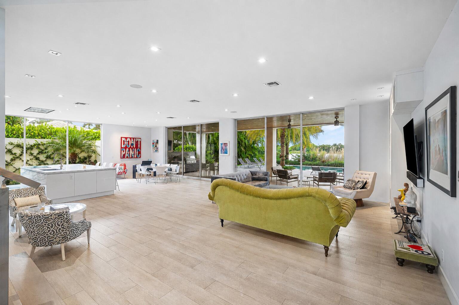 A spacious open-concept living area with light wood floors, a kitchen, and floor-to-ceiling glass doors — 1508 Lake Drive, Delray Beach FL 33444, DELRAY BEACH, FL