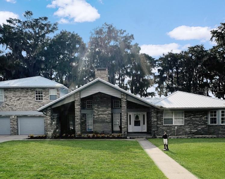 A single-story brick house with a metal roof, a prominent front gable, and a two-car garage — 15618 SE US HIGHWAY 301, HAWTHORNE, FL