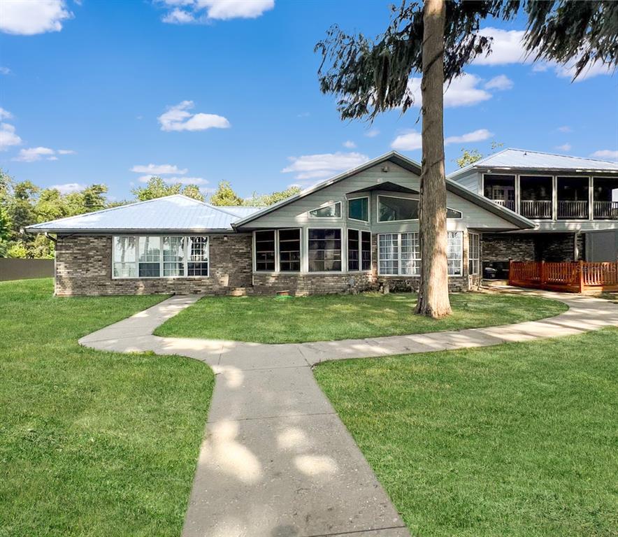 A brick house with a metal roof, large windows, and a concrete walkway in the yard — 15618 SE US HIGHWAY 301, HAWTHORNE, FL