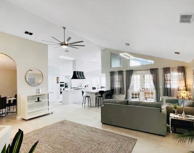 An open-concept living room and kitchen featuring vaulted ceilings, a large island, and tile flooring — 15618 SE US HIGHWAY 301, HAWTHORNE, FL