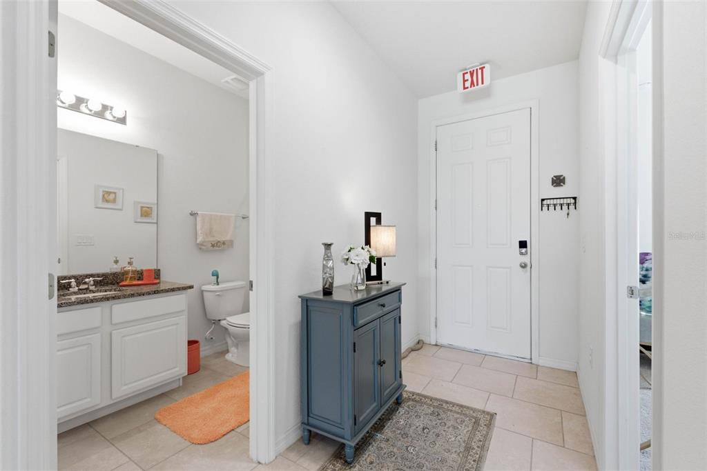 An entryway with a blue cabinet, tile flooring, and a doorway leading to a bathroom — 4702 TERRASONESTA DRIVE, DAVENPORT, FL