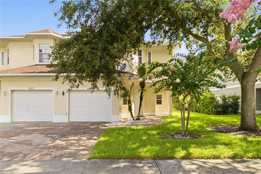 A two-story townhouse with a two-car garage, light-colored stucco exterior, and a paved driveway — 455 WESTPOINT GARDEN CIRCLE, WINTER GARDEN, FL