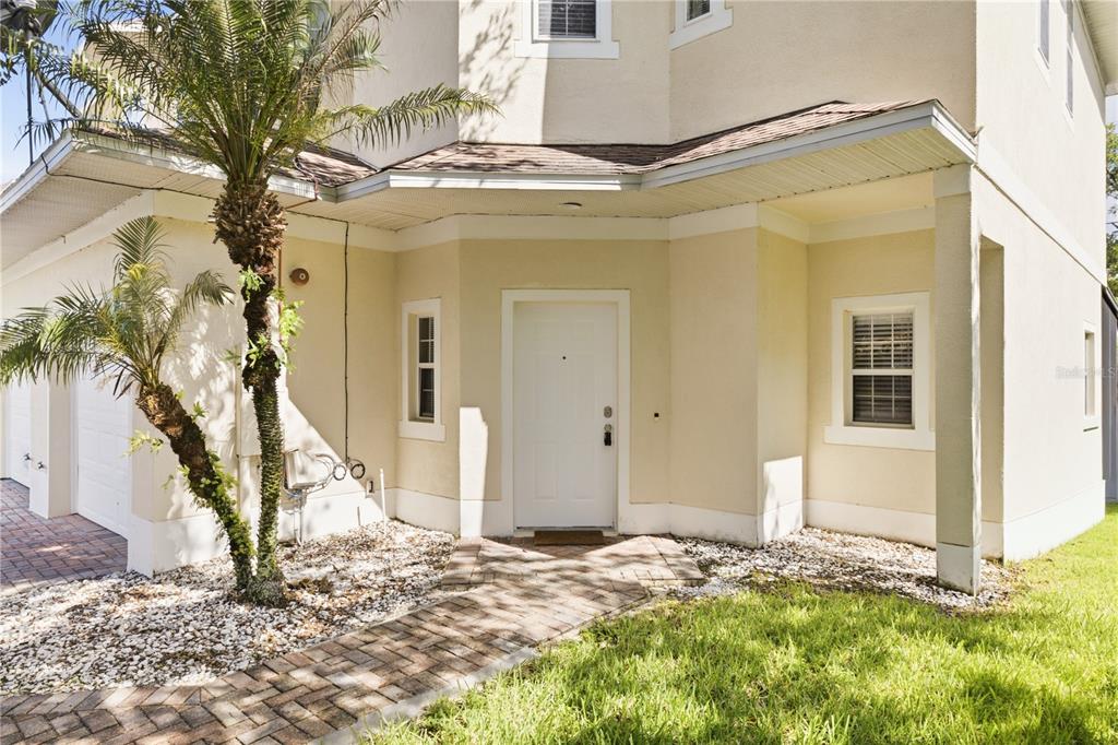 A paved walkway leads to the white front door of a two-story beige house — 455 WESTPOINT GARDEN CIRCLE, WINTER GARDEN, FL