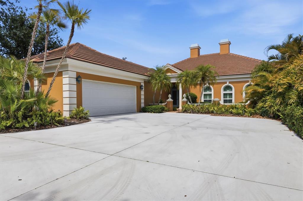 A single-story house with an orange stucco exterior, a tile roof, and a concrete driveway — 84 CAYMAN ISLES BOULEVARD, ENGLEWOOD, FL