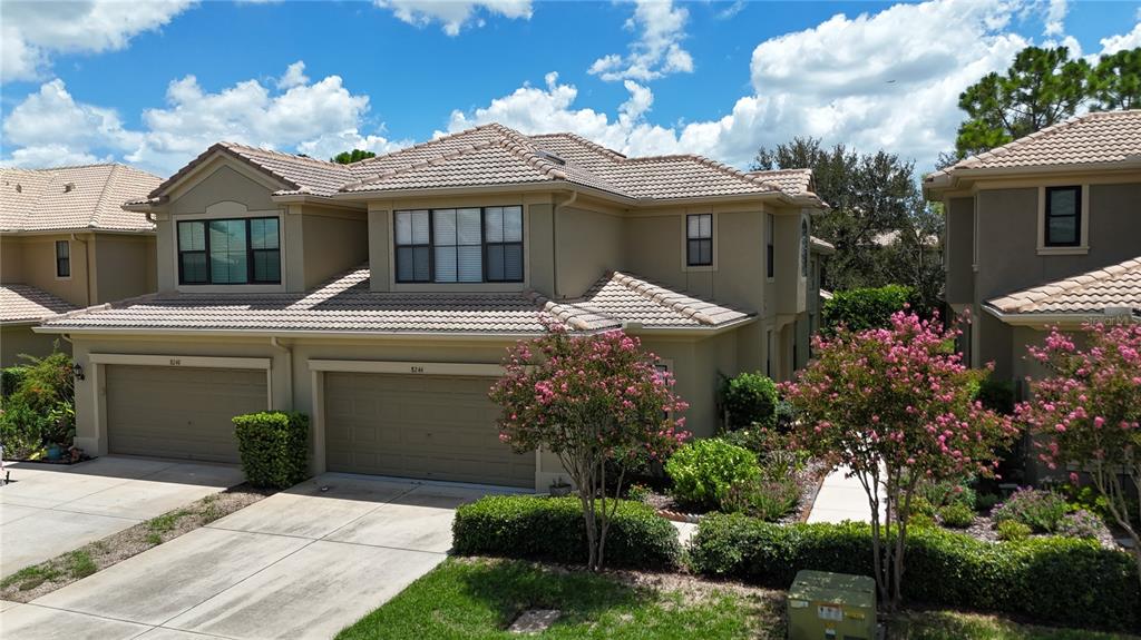 An exterior view of a two-story townhouse with a tiled roof and two garage doors — 8240 ACADIAN LANE, SEMINOLE, FL