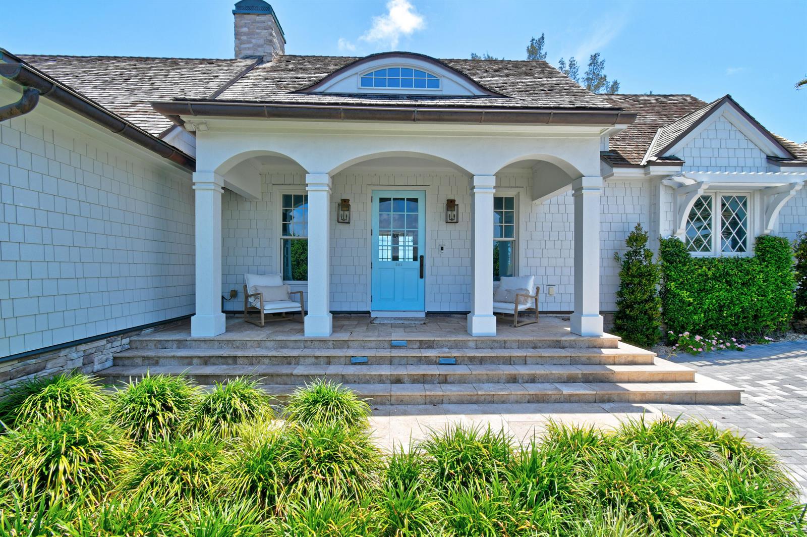 The exterior of a white shingled house features a covered porch with a blue door — 282 Celestial Way, Juno Beach FL 33408, JUNO BEACH, FL