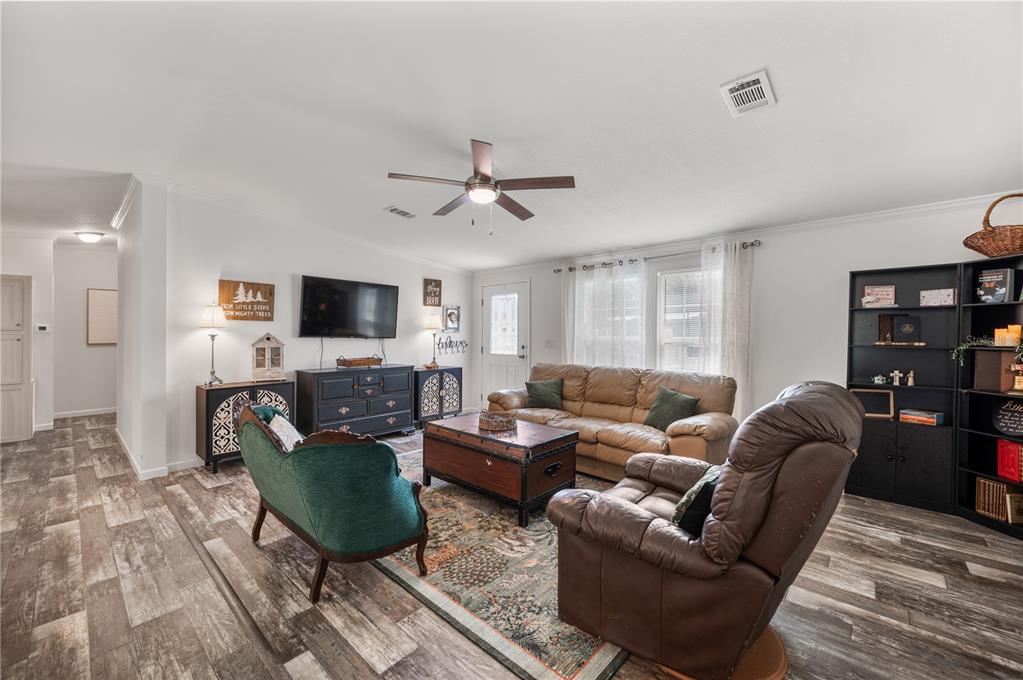 A living room features a ceiling fan, wood-look flooring, a television, and assorted furniture — 1321 WINDSONG DRIVE, LAKELAND, FL