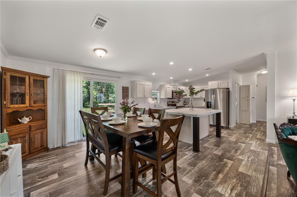 A dining area with a wooden table and hutch opens into a modern white kitchen — 1321 WINDSONG DRIVE, LAKELAND, FL