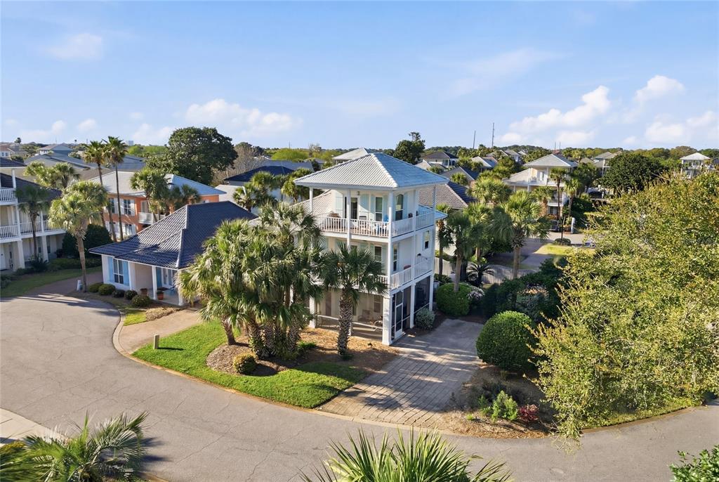An elevated coastal house with a metal roof and wraparound porches sits on a corner lot — 26 TOPAZ COVE, MIRAMAR BEACH, FL