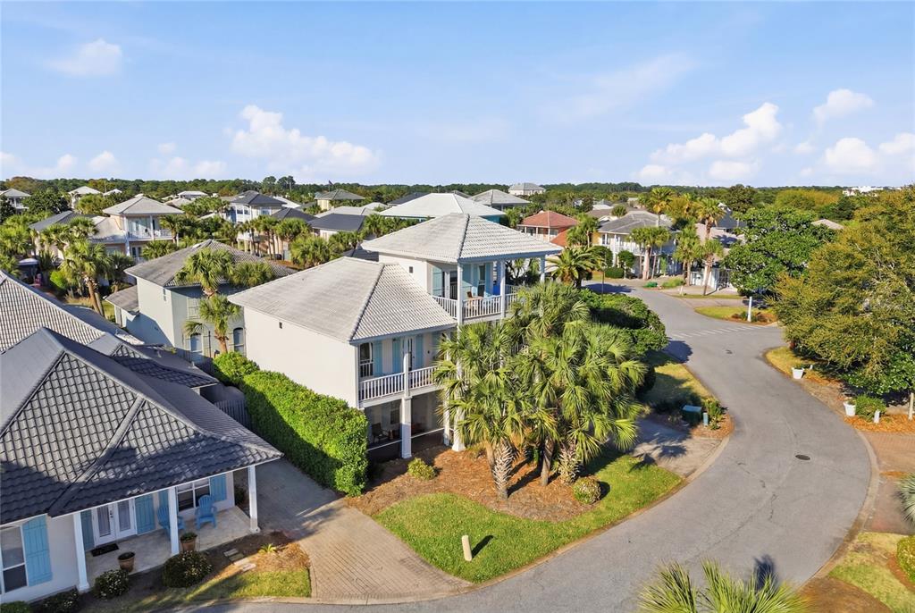 An aerial view shows a multi-story coastal house with a tiled roof and palm trees — 26 TOPAZ COVE, MIRAMAR BEACH, FL
