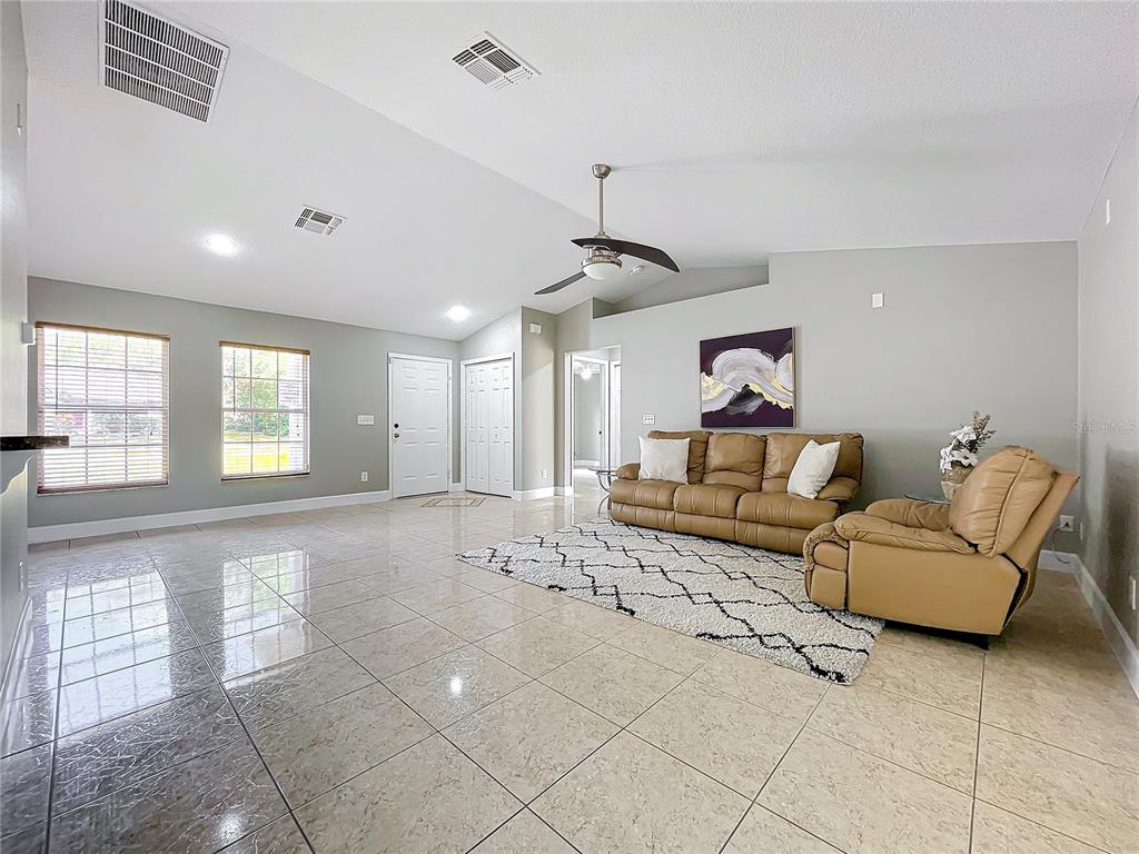 A living room features light-colored tile flooring, a vaulted ceiling, and a tan leather sofa set — 790 SILHOUETTE COURT, LONGWOOD, FL