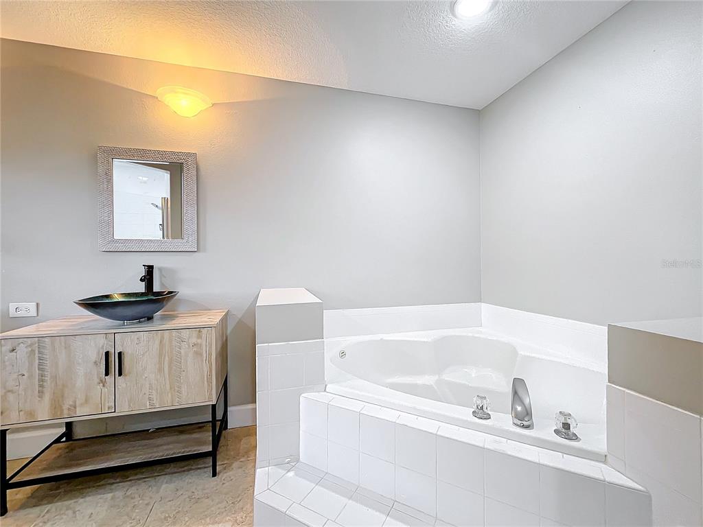 A bathroom features a vessel sink vanity, a tiled corner jetted tub, and neutral walls — 790 SILHOUETTE COURT, LONGWOOD, FL