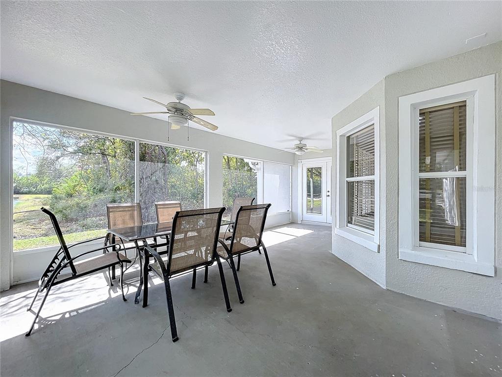 A screened-in patio features a dining set, ceiling fans, and views of a wooded area — 790 SILHOUETTE COURT, LONGWOOD, FL