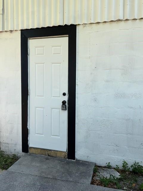 A white six-panel door with a black frame is set into a white concrete block wall — 1125 OLIVE STREET, LAKELAND, FL