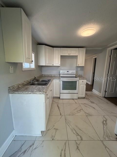 A kitchen features white cabinets, granite countertops, a white stove, and light-colored marble-patterned floor tiles — 1125 OLIVE STREET, LAKELAND, FL
