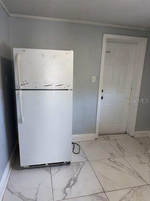 A white refrigerator stands on a white marble-patterned tiled floor next to a white door — 1125 OLIVE STREET, LAKELAND, FL