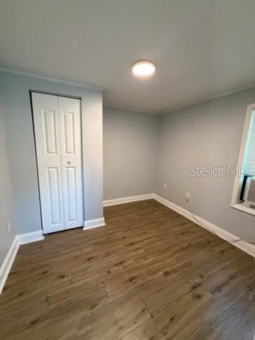 A bedroom with light gray walls, wood-look flooring, a white closet door, and a window — 1125 OLIVE STREET, LAKELAND, FL