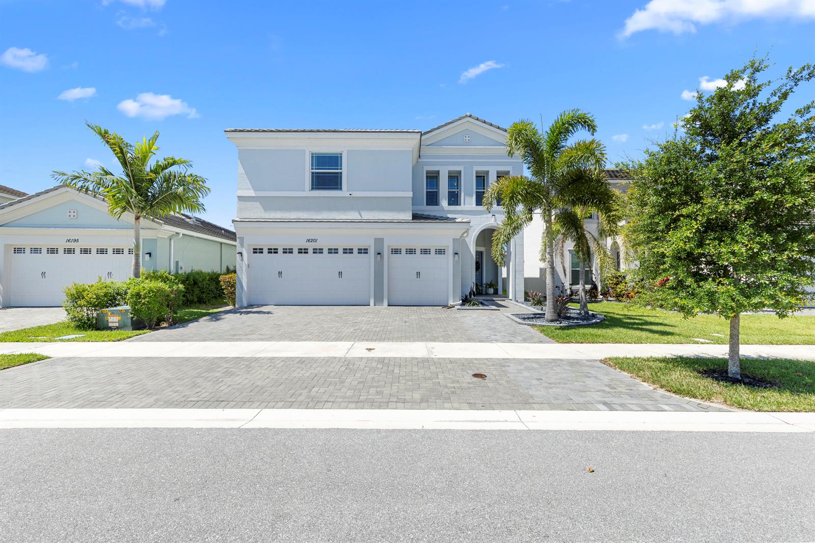 A two-story house with a paved driveway, two garage doors, and palm trees in front — 16201 Melogold Drive, Westlake FL 33470, WESTLAKE, FL