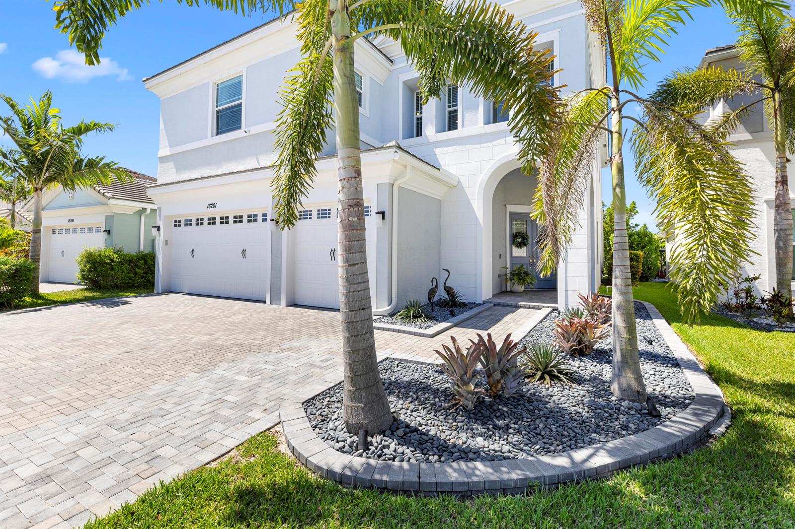 A two-story house with a paved driveway, palm trees, and a landscaped front garden — 16201 Melogold Drive, Westlake FL 33470, WESTLAKE, FL
